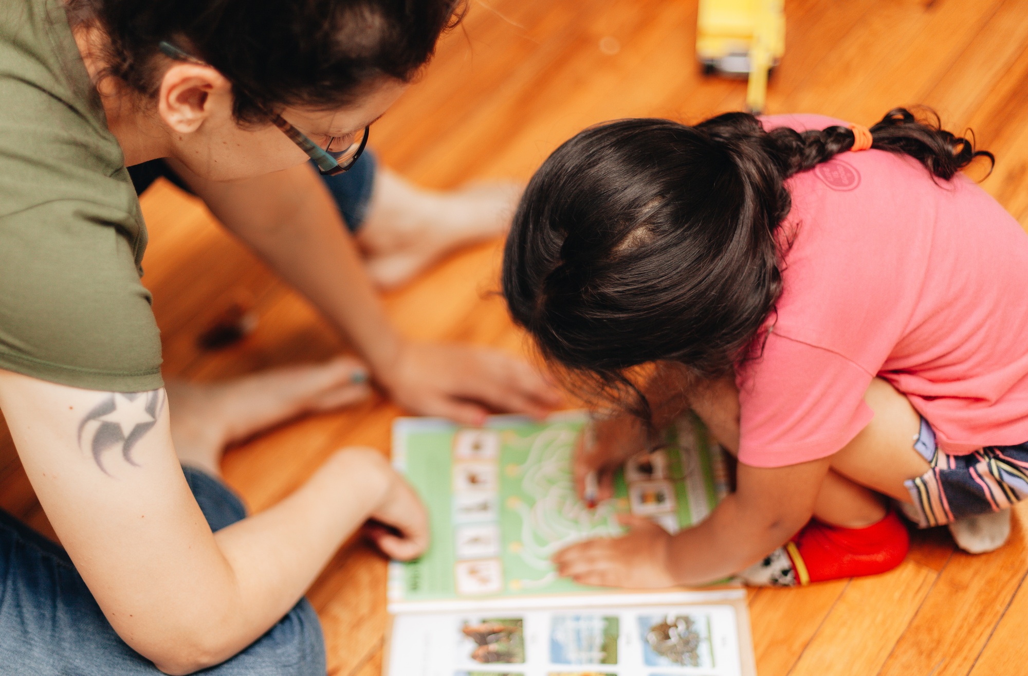 Mother and diverse daughter at home playing a game from a book, bonding, early education