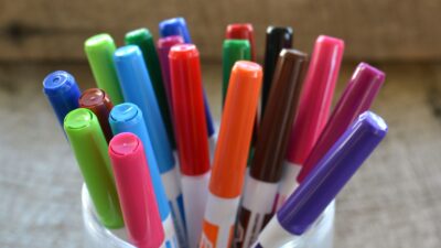 Colorful white board dry erase magic markers in a container on a desk.