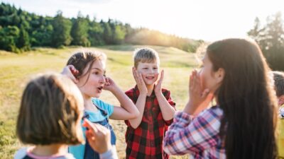 Group of school children standing on field trip in nature, playing