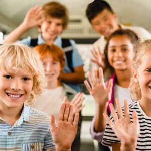 Happy mixed-race multiethnic schoolchildren classmates kids pupils sitting inside school bus
