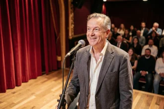 Comédien français sur scène en plein sketch humoristique dans un cabaret parisien, microphone en main