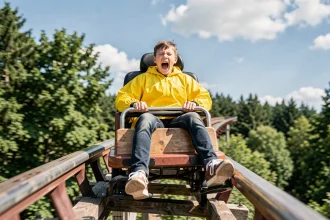 Adolescent criant de plaisir dans les montagnes russes du Parc La Panne lors d'une descente vertigineuse